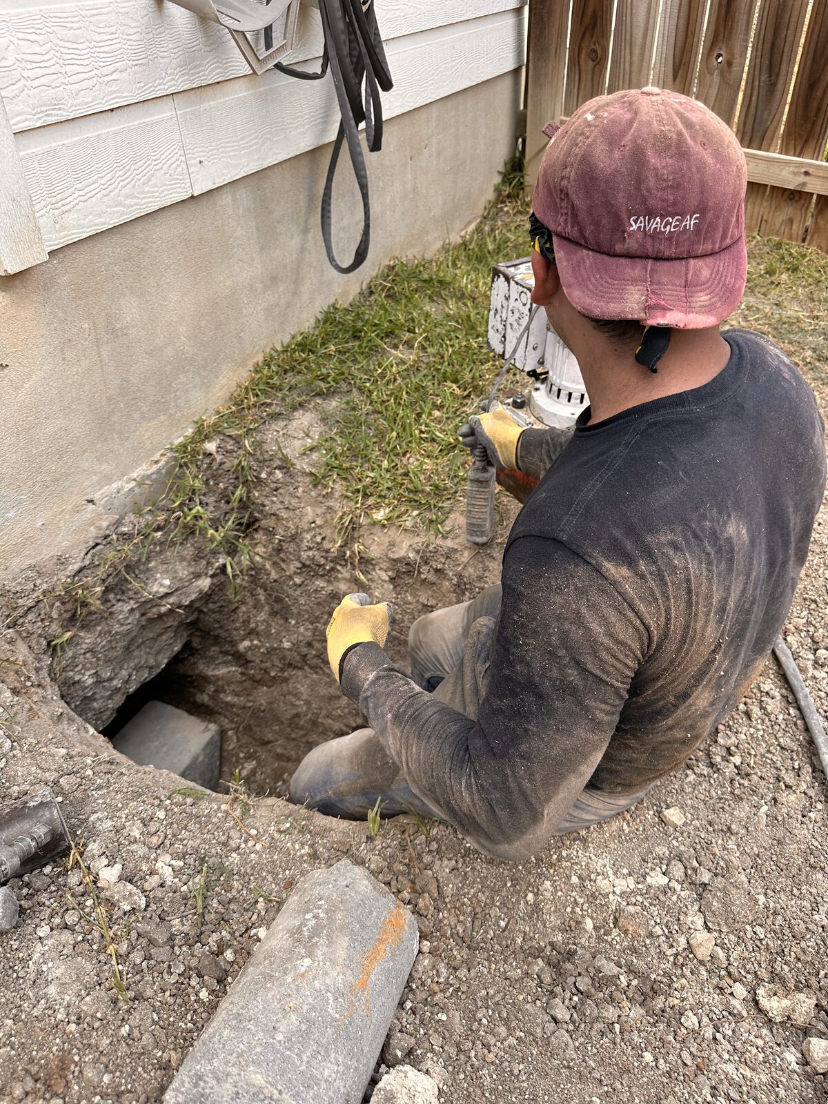 Crew member operating a hydraulic ram to press concrete pilings beneath a home's foundation